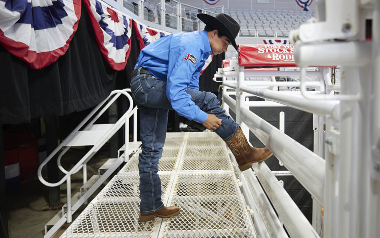 Laramie Mosley models a brown boot with his foot propped up on the chutes at the Fort Worth Stock Show & Rodeo.